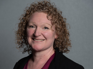 Sarah Minson smiling. She has curly above-shoulder hair.